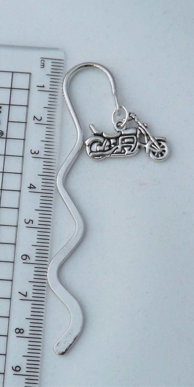 May include: Silver bookmark with a motorcycle charm. The bookmark is approximately 8 inches long and has a wavy design.