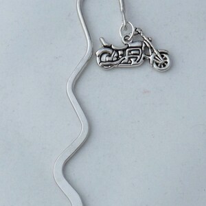 May include: Silver bookmark with a silver motorcycle charm. The bookmark is shaped like a wavy line.