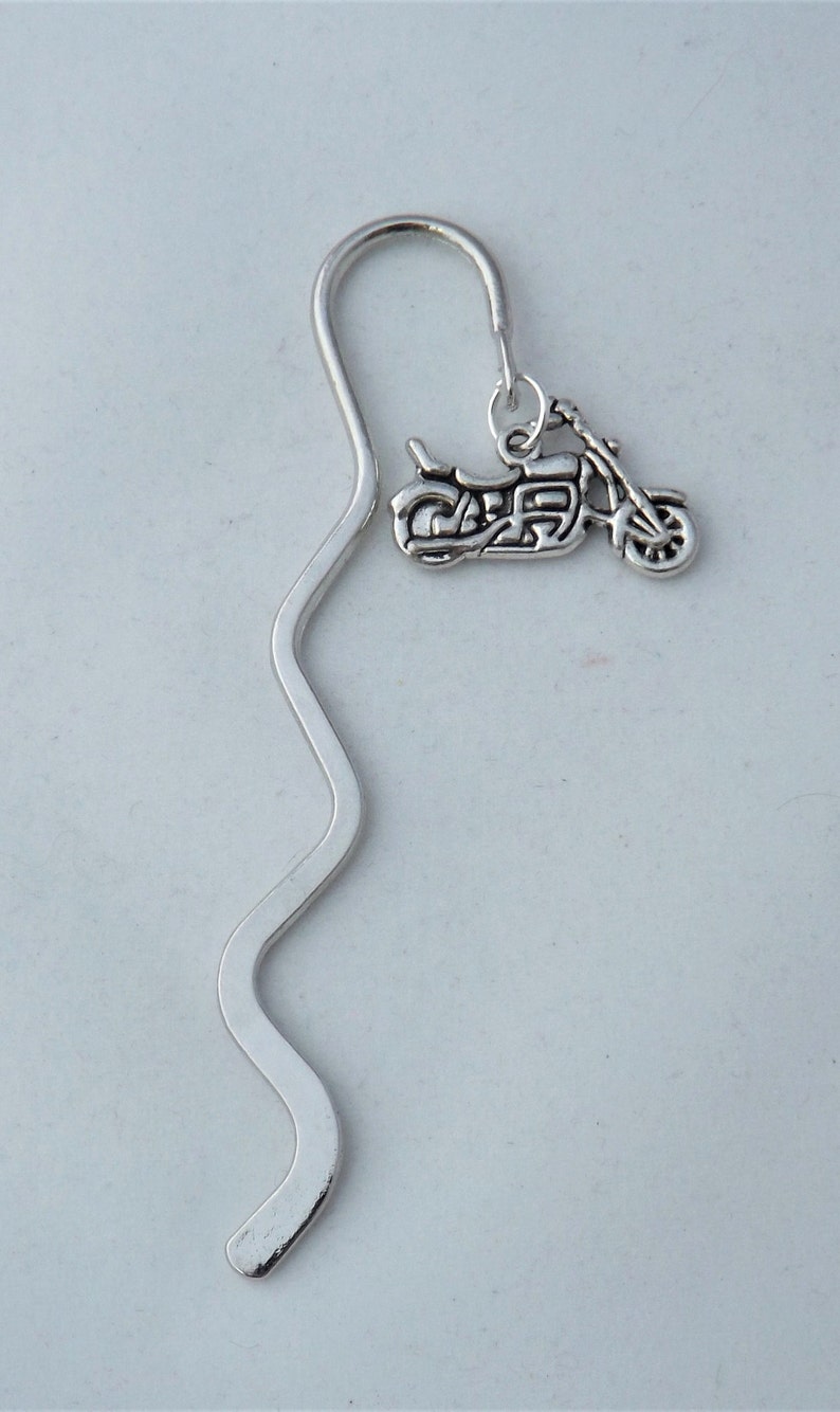 May include: Silver bookmark with a silver motorcycle charm. The bookmark is shaped like a wavy line.