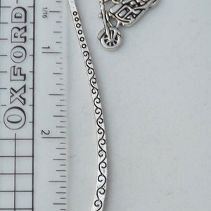 May include: Silver bookmark with a motorcycle charm. The bookmark is approximately 7.6 cm long and features a decorative design along the edge.