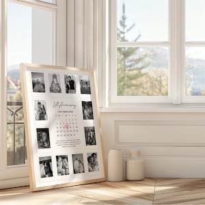 May include: A framed collage featuring black and white photographs, arranged around a calendar. The calendar highlights a specific date with a heart symbol, and the text reads "1st Anniversary October 2025". The frame is light-colored wood.