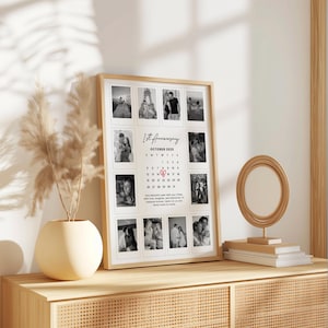 May include: A framed photo collage commemorating a 1st anniversary, featuring a series of black and white photos. The frame is light-colored wood, and the collage includes a calendar for October 2025. Text reads "1st Anniversary".