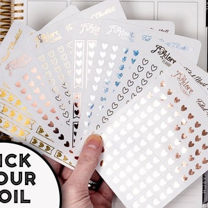 May include: A set of six heart-shaped sticker sheets with different foil finishes. The sheets are labeled "Fitted Heart Checklists" and feature a variety of heart sizes and designs. The foil finishes include gold, rose gold, silver, and blue.