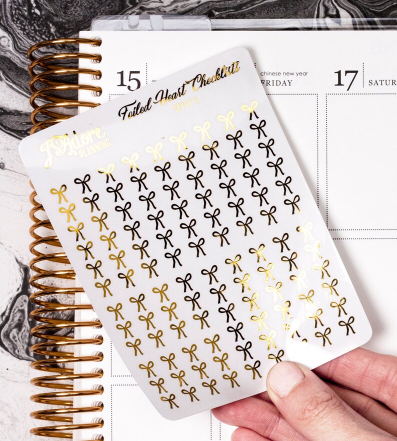 May include: A sheet of gold and black bow stickers with the text "Failed Heart Checklist" and "Adore Planning" on the sheet.