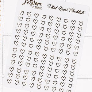 May include: A sheet of clear stickers with black outlines of hearts. The sheet has the text "Foiled Heart Checklists" printed on it.