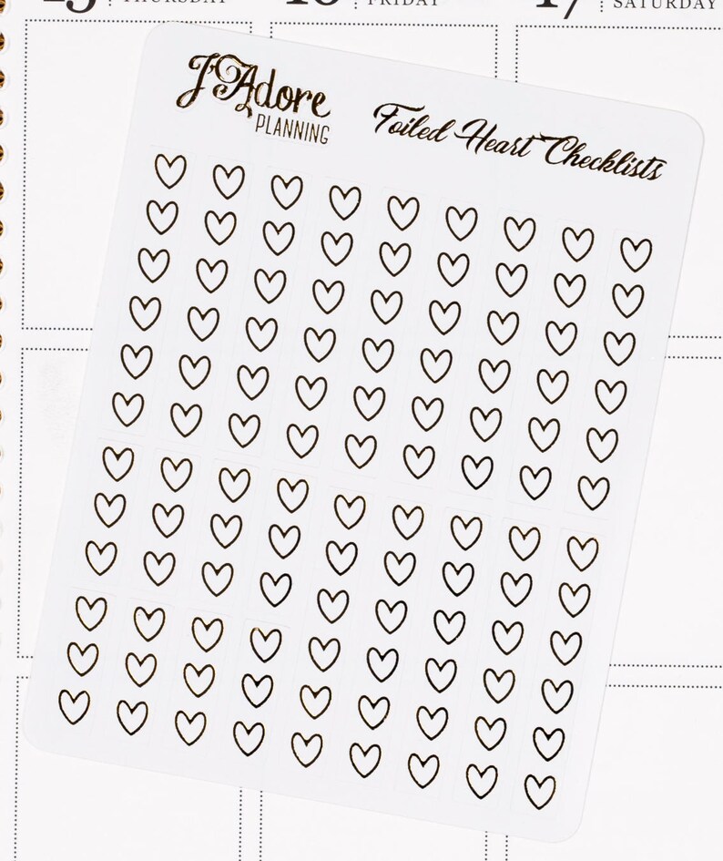 May include: A sheet of clear stickers with black outlines of hearts. The sheet has the text "Foiled Heart Checklists" printed on it.
