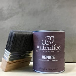 May include: A paint can and a paintbrush are displayed against a gray background. The paint can is dark purple with the text "Autentico" and "Venice" printed on it. The paintbrush has a wooden handle and black bristles.