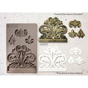 May include: A silicone mold for making decorative resin pieces. The mold features a large ornate design with smaller accent pieces. The finished pieces are shown in gold and white.