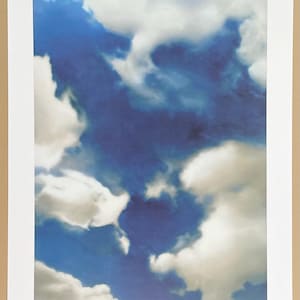 May include: A photograph of a blue sky with white clouds. The clouds are fluffy and appear to be moving across the sky.