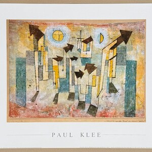 May include: A rectangular art print featuring a Paul Klee painting with abstract geometric shapes, arrows, and celestial forms in shades of yellow, blue, and brown. The name PAUL KLEE is printed in black capital letters centered below the artwork.