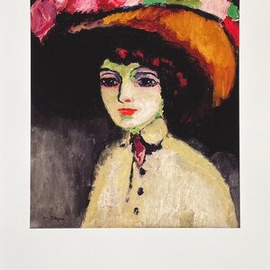 Può includere: Una stampa de "La Parisienne de Montmartre, 1908" di Kees van Dongen. Il dipinto raffigura una donna con carnagione pallida, labbra rosse e occhi scuri, che indossa un grande cappello ornato di rose rosa. Indossa un cappotto color crema.