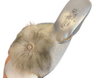 May include: Silver faux fur slippers with a sparkly snowflake embellishment. The slippers are labeled "Foam Cushioned Made in U.S.A."
