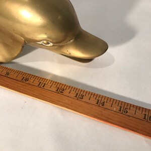 May include: A gold-colored metal dolphin figurine. The dolphin is about 12 inches long.