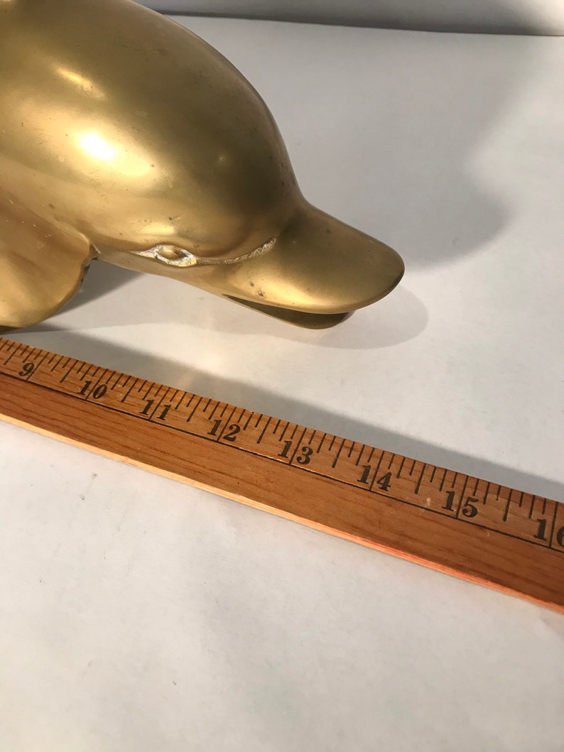 May include: A gold-colored metal dolphin figurine. The dolphin is about 12 inches long.