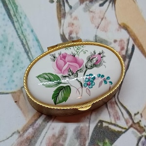 Boîte à pilules ovale dorée avec un insert en céramique décoré de myosotis roses et bleus