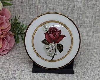 Polvos compactos ~ Rosa rosa rojiza sobre una cúpula de porcelana rodeada por un borde de esmalte blanco.