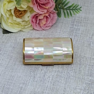 May include: A white ceramic mug with a black handle and the text "But first, coffee" in a black, handwritten-style font. The mug is on a white surface.