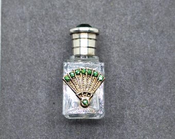 Frasco de perfume pequeño con adorno de abanico dorado y diamantes de imitación verdes.