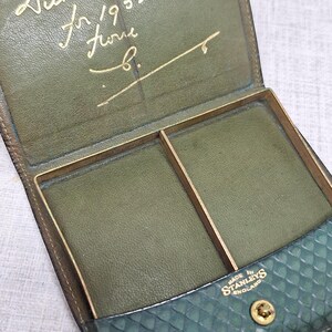 Pu&ograve; includere: Portafoglio vintage aperto in pelle verde con dettagli dorati. L'interno presenta due scomparti e un'iscrizione dorata. L'esterno ha una sezione strutturata e fantasia. Marchiato "Made in Stanleys England."