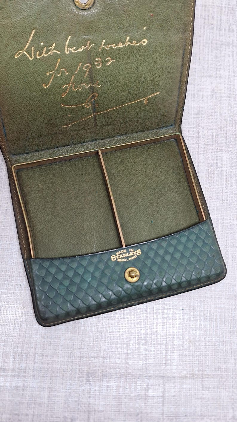 Pu&ograve; includere: Astuccio vintage in pelle verde aperto, che rivela due scomparti. Il lembo anteriore presenta un motivo strutturato. All'interno, la scritta dorata recita "Liz best wishes for 1952". Marchiato "MADE IN STANLEYS ENGLAND".