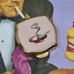 Cendrier portable Stratton ~ émail rose avec une cigarette qui fume dans un cendrier rouge ~ vintage milieu du siècle