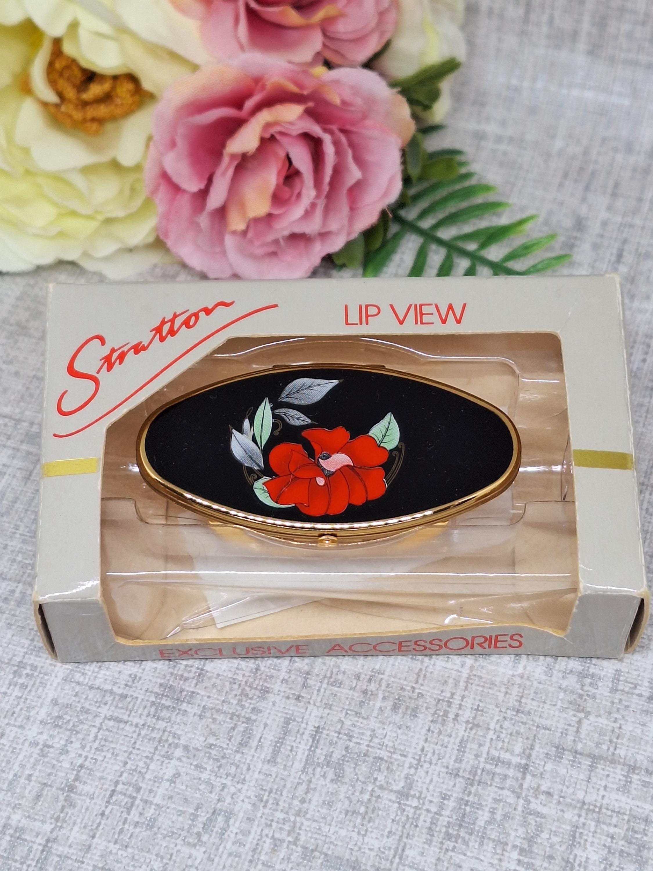 Pinza para lápiz labial Stratton Lipview en esmalte negro, decorada con flores rojas y hojas verdes grises. Estuche para lápiz labial de los años 80 con mini espejo.