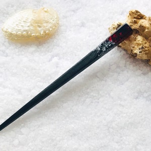 May include: A black and red hair stick with a clear resin section containing silver glitter. The stick is about 10 inches long.
