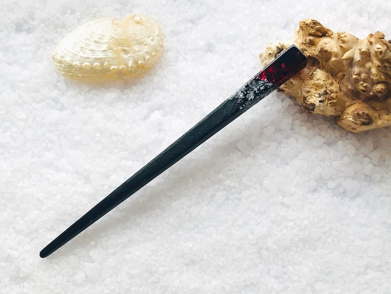 May include: A black and red hair stick with a clear resin section containing silver glitter. The stick is about 10 inches long.