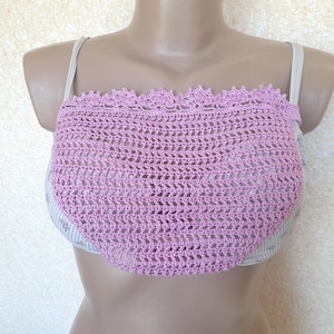 May include: A light purple crochet top with a scalloped edge. The top is made of a delicate, open-weave crochet pattern. The top is displayed on a mannequin.