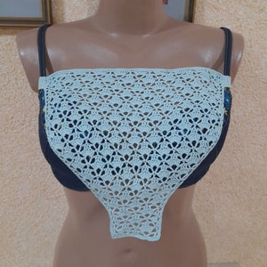 May include: A light blue crocheted top with a delicate pattern. The top is sleeveless and has a scoop neckline.