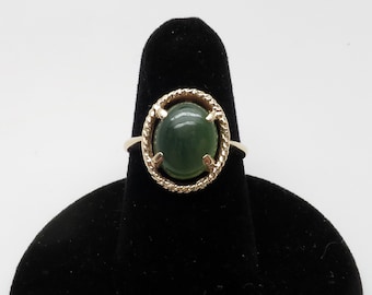 May include: A gold ring with a green oval gemstone set in a rope-like design.