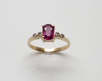 May include: A gold ring with a pink oval gemstone and smaller clear gemstones on the band.