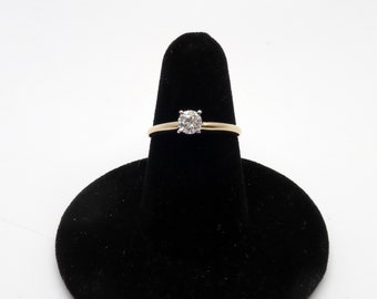 Könnte beinhalten: Ein Goldring mit einem einzelnen runden Diamanten in der Mitte.