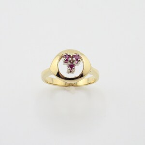 Può includere: Un anello d'oro con un'apertura a forma di cuore e un gruppo di pietre preziose rosa al centro.