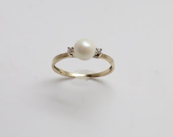 May include: A gold ring with a single white pearl and two small diamonds.