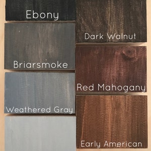 May include: Six wood stain samples in different shades of brown, gray, and black. The samples are labeled with the following names: Ebony, Dark Walnut, Briarsmoke, Red Mahogany, Weathered Gray, and Sunbleached.