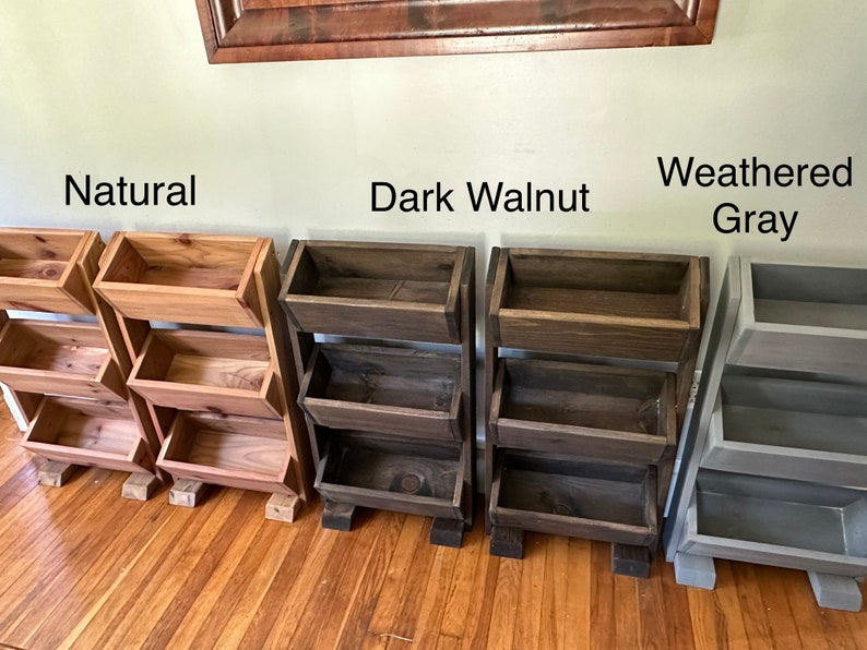 May include: Three wooden shelf units with three shelves each. The shelves are in three different finishes: natural, dark walnut, and weathered gray.