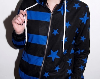 May include: A black zip-up hoodie featuring a split design. The left side displays horizontal blue stripes, while the right side and sleeves are covered in blue stars. The garment includes a hood with white drawstrings and a silver metal zipper.