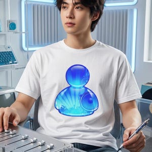 May include: White t-shirt featuring a blue graphic design. The design is a stylized figure with a large head and a speaker on the torso, with a background of radiating lines and musical elements. The shirt is worn by a person.