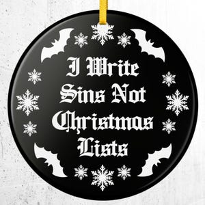 May include: A round black ceramic ornament featuring the white text "I Write Sins Not Christmas Lists" in a gothic font. The design is surrounded by a border of white snowflakes and bat silhouettes, with a yellow ribbon for hanging.