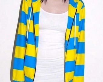 May include: A zip-up hoodie featuring horizontal yellow and blue stripes, paired with a plain white tank top and matching yellow and blue striped leggings. The hoodie includes a hood with white drawstrings and ribbed cuffs at the sleeves.
