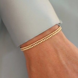 May include: A gold beaded bracelet with two rows of beads.