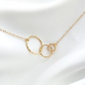 Peut inclure: Collier en or avec trois cercles entrelacés. Les cercles sont de tailles différentes et ont une texture martelée.