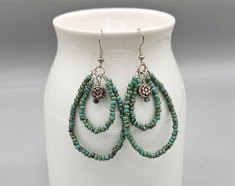 May include: Teal and silver dangle earrings with three layers of beads and a flower charm.