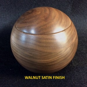 May include: A round wooden box with a lid, made of walnut wood with a satin finish.