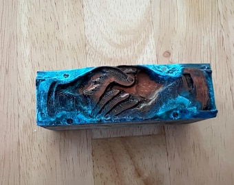 Antique letterpress printing block.  Metal on top of wood. Two hands