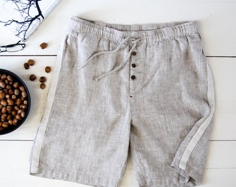 May include: Light gray linen shorts with white side stripes and a drawstring waist.