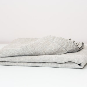 May include: A folded gray linen throw blanket. The blanket is made of a soft, natural fabric and has a slightly textured surface.