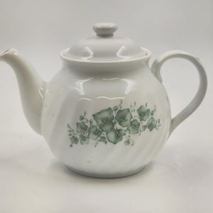 以下が含まれることがあります： 蓋と取っ手が付いた白いセラミックティーポット。 ティーポットの側面には、緑と灰色のツタの葉のデザインがあります。 ティーポットは、湾曲した注ぎ口と蓋の小さなノブを備えています。 お茶を淹れるように設計されています。