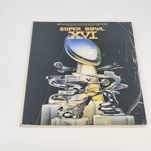 Può includere: Un programma vintage del Super Bowl XVI con una copertina nera. La copertina presenta il logo del Super Bowl XVI e un trofeo d'argento con un pallone da football in cima. Lo sfondo è nero con accenti argentati e grigi.
